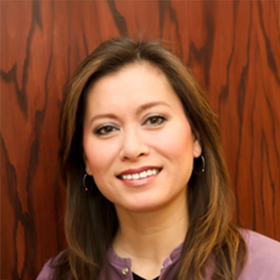 Pediatric Dentist Dawn Yuen Harvey Smiling In Front Of Wood Wall
