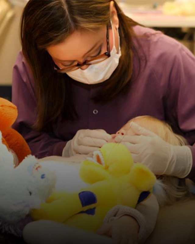 Pediatric Dentist Dawn Yuen Harvey Examining Patient Holding A Stuffed Animal