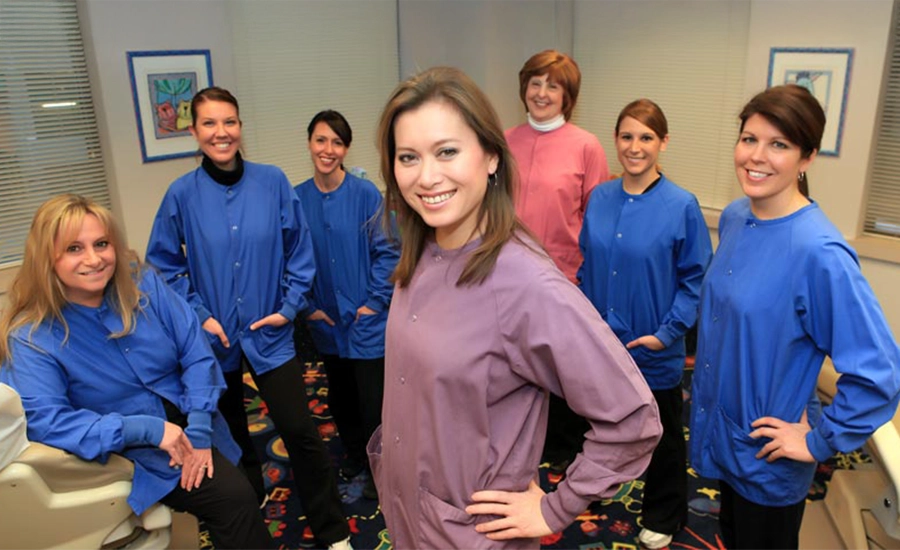 Pediatric Dentist Dawn Yuen Harvey With Her Team In Scrubs Smiling