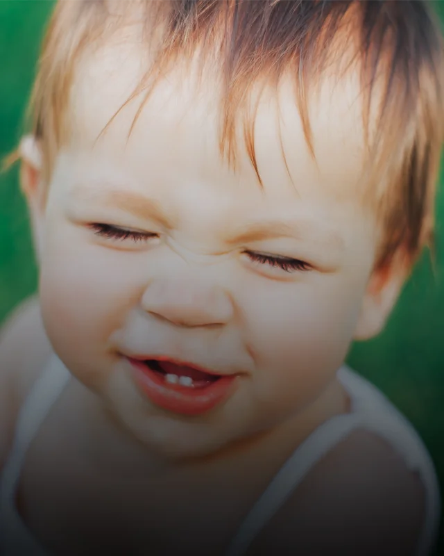 A young child grimacing in pain as new teeth grow in