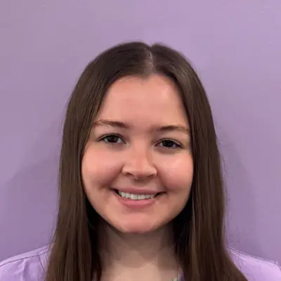 Hannah smiling at the camera while wearing a lavender top